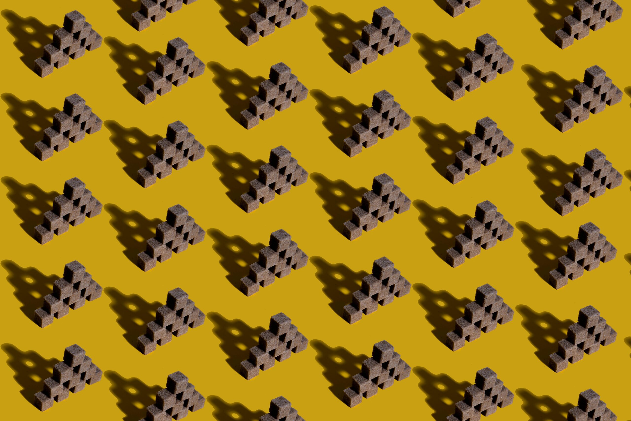 Abstract geometric pattern featuring pyramids creating shadows on a yellow background.