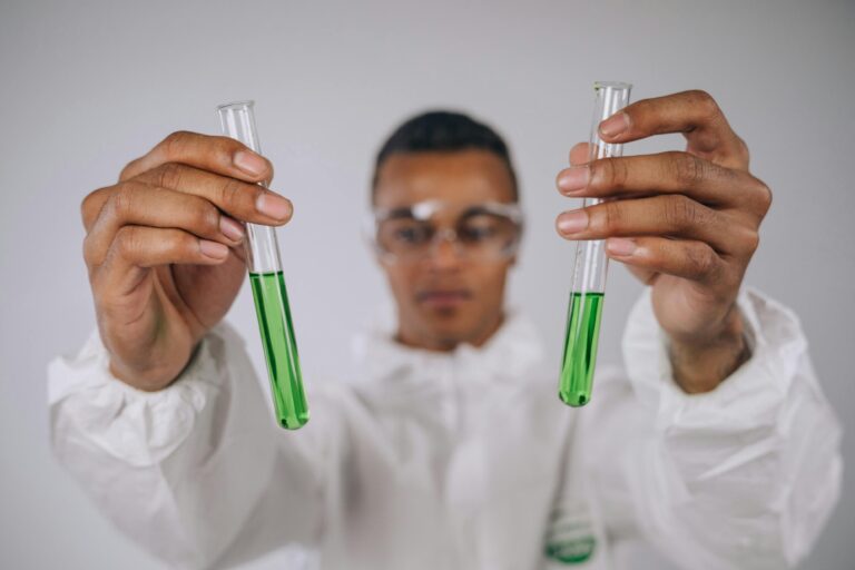 Focused scientist examining green liquid in test tubes, conducting research