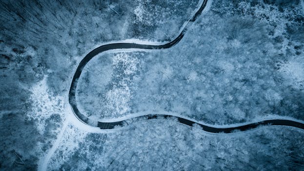 A scenic aerial shot of a winding road through a snow-covered forest in Croatia during winter.